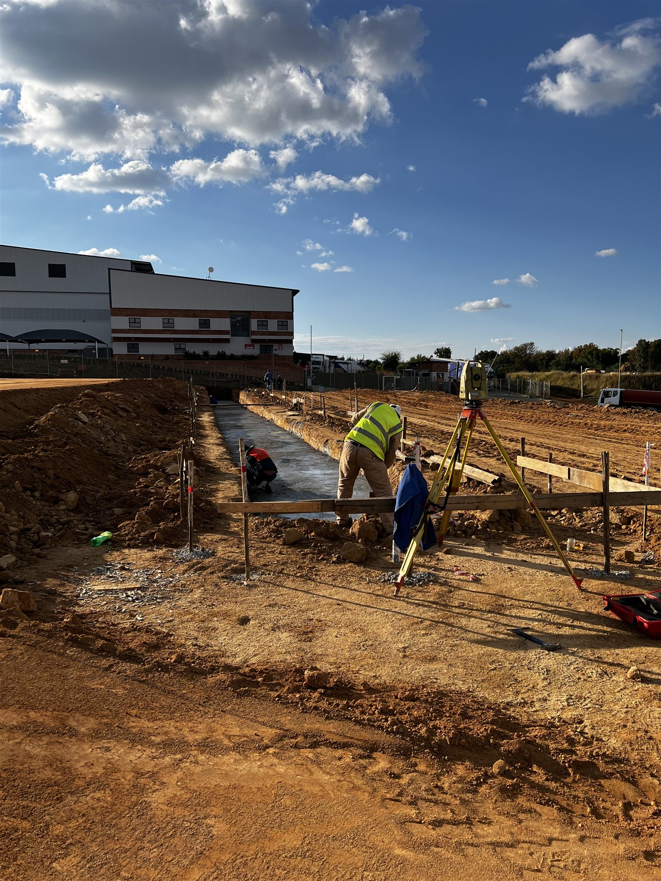 Surveyor using a total station beside foundation formwork