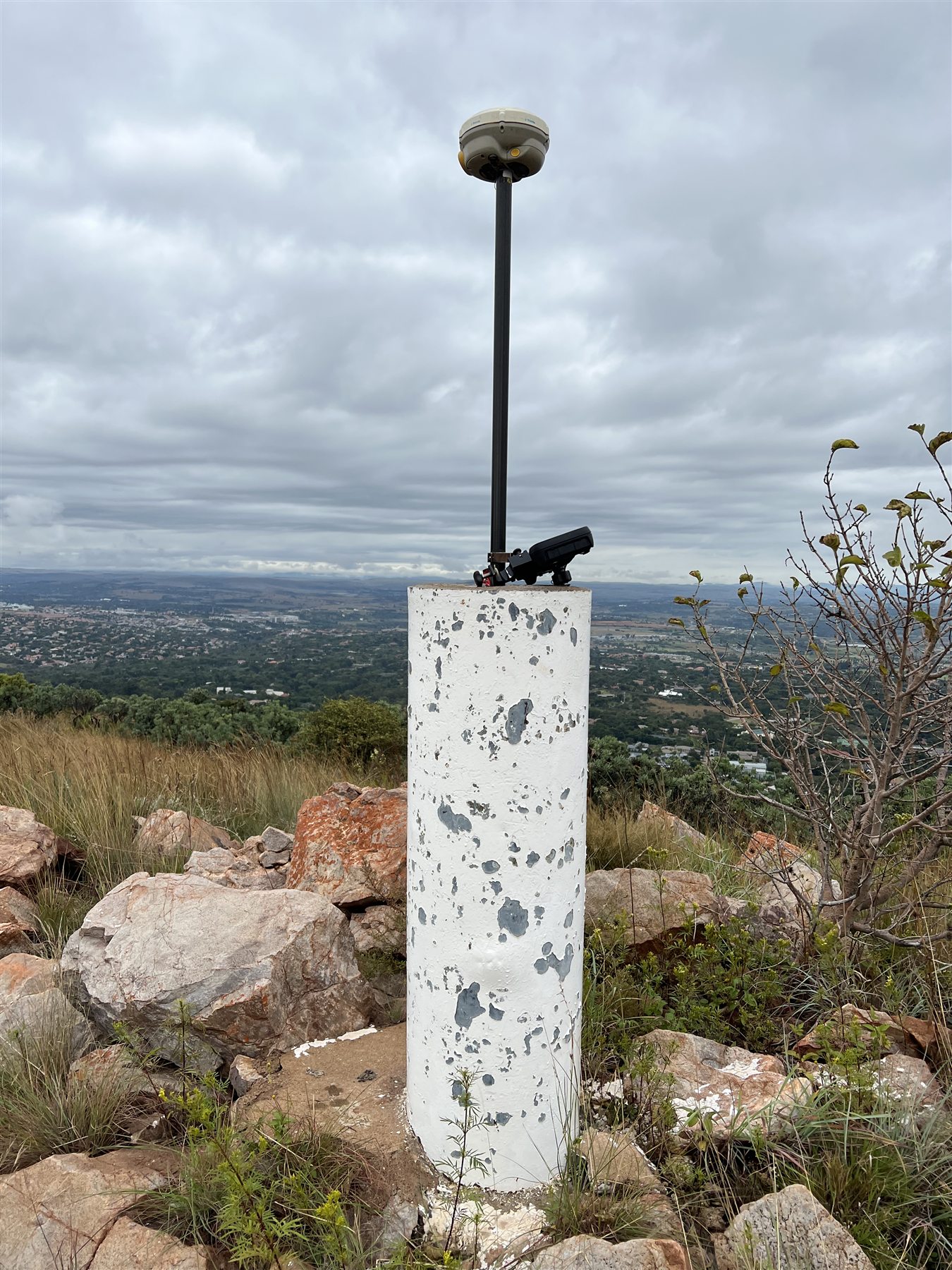GNSS receiver occupying an elevated survey pillar above a valley