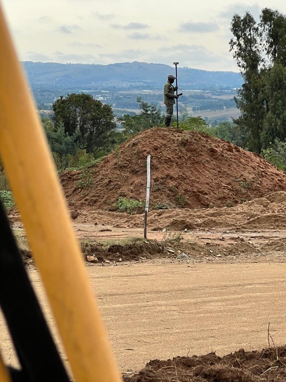 Surveyor using a GNSS rover across open terrain